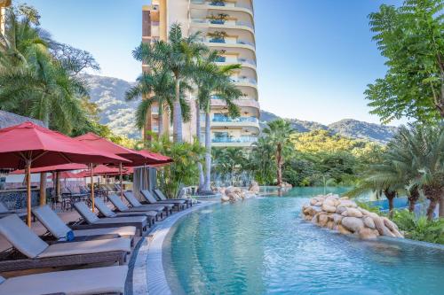a pool at a resort with lounge chairs and palm trees at Garza Blanca Preserve Resort & Spa Puerto Vallarta in Puerto Vallarta