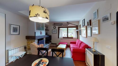a living room with a red couch and a fireplace at Los Altos de Escarrilla - tucasaenlospirineos in Escarrilla