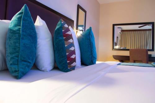 a bedroom with a bed with blue and white pillows at Best Western Plus Accra Beach Hotel in Teshi