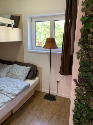 a small bedroom with a bed and a floor lamp at Balatonic apartman in Zamárdi
