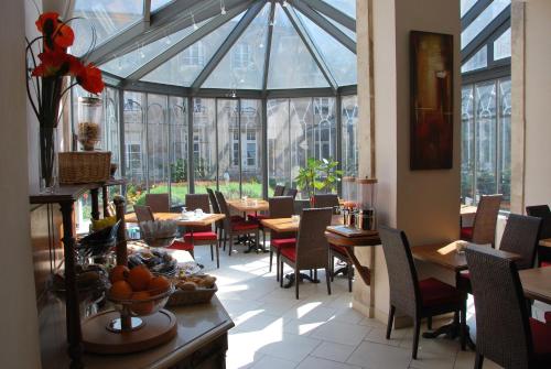 un restaurante con mesas y sillas en una habitación con ventanas en Hotel Des Prélats, en Nancy