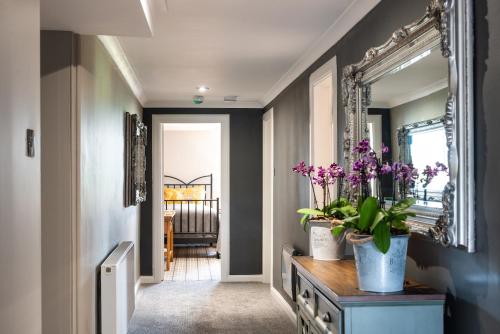 a hallway with a mirror and purple flowers on a dresser at Blanerne House in Duns