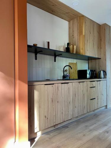 a kitchen with wooden cabinets and a sink at Domki MODERN Jezioro Nyskie in Nysa