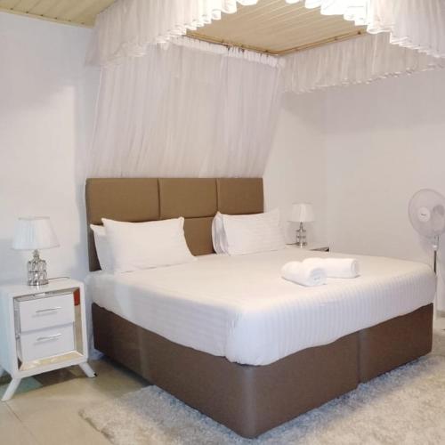a bedroom with a large bed with white sheets at Sofitel 3 bedrooms own compound milimani in Kisumu