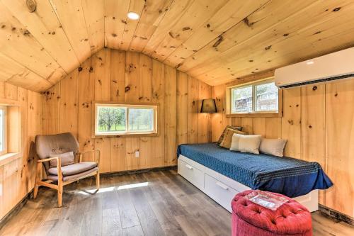 a bed and a chair in a room with wooden walls at Cozy Upstate Studio with Walkill River Views! in New Paltz