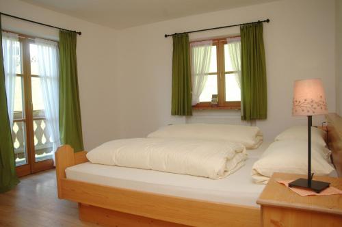 a bedroom with two beds with green curtains and a lamp at Haus Sonnenruh in Mittenwald