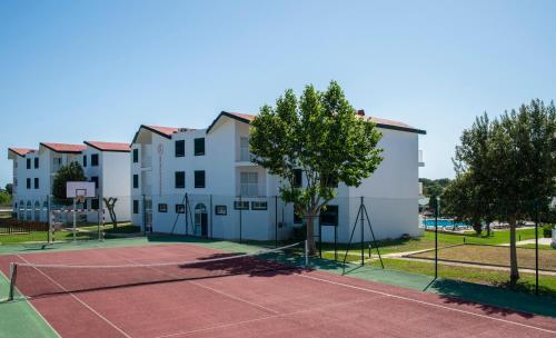 a tennis court in front of a building at Pierre & Vacances Menorca Cala Blanes in Cala en Blanes