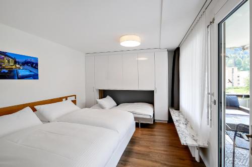 two beds in a room with white walls and a window at Apartment nearby Titlis Station in Engelberg