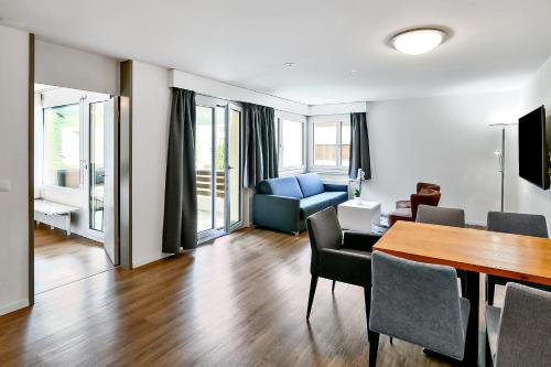 a living room with a table and chairs and a couch at Apartment nearby Titlis Station in Engelberg