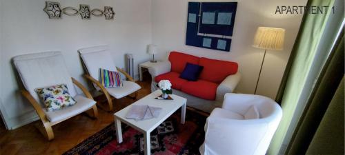uma sala de estar com um sofá vermelho e duas cadeiras em Charming Family Apartment em Lisboa