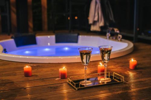 zwei Gläser Wein und Kerzen auf einem Tisch mit einer Badewanne in der Unterkunft In Heaven in Zdów