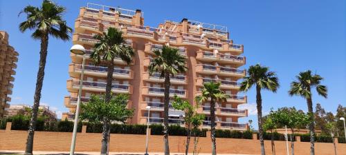 a tall building with palm trees in front of it at ACV - Playa Dorada -1ª Linea planta 3 norte in Oropesa del Mar