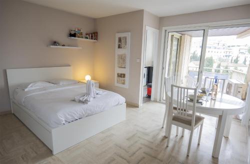 a white bedroom with a white bed and a table at Maresol in Cagnes-sur-Mer