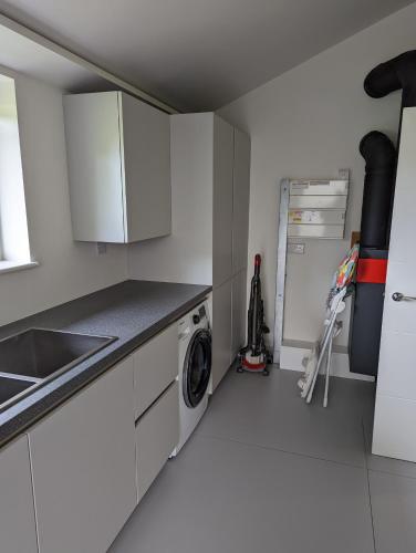 a kitchen with white cabinets and a washing machine at Unique, Spacious, Self-Built Eco Home with huge garden and movie room in Andover
