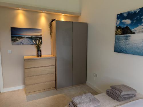 a bedroom with a cabinet and a painting on the wall at Unique, Spacious, Self-Built Eco Home with huge garden and movie room in Andover