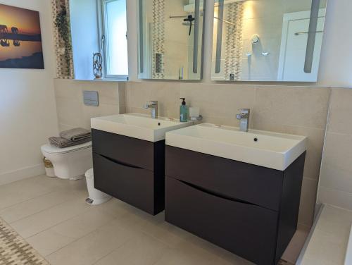 a bathroom with two sinks and a toilet at Unique, Spacious, Self-Built Eco Home with huge garden and movie room in Andover