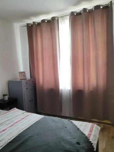 a bedroom with a bed and a window with curtains at Arsan home in Cluj-Napoca