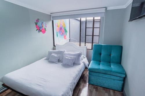 a bedroom with a bed and a blue chair at ApartaSuites & Hotel Bogota Suamox in Bogotá