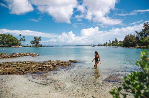 a woman walking in the water on a beach at SCP Hilo Hotel in Hilo