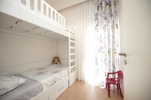 a white bedroom with a bunk bed and a window at ROGA Apartment Valamar in Hamallë