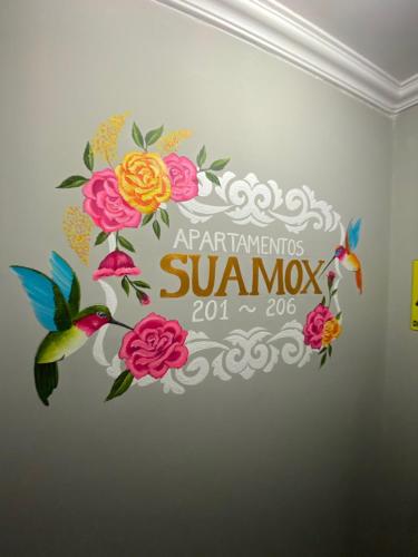 a sign on a wall with flowers and butterflies at ApartaSuites & Hotel Bogota Suamox in Bogotá