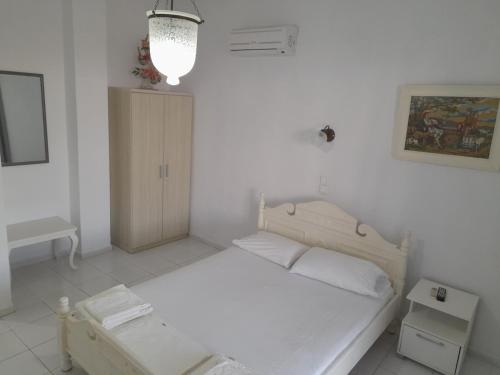 a small white bedroom with a bed and a table at Silver view in Batsi