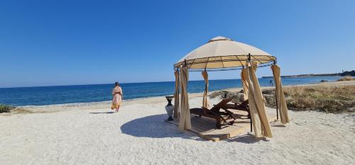 a woman walking on a beach with a gazebo at Villa del Mar in Mazotos
