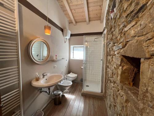 baño con pared de piedra, lavabo y aseo en Agriturismo B&B Luna di Quarazzana in Fivizzano Tuscany, en Fivizzano