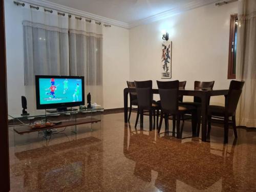 a dining room with a table and chairs and a television at KARIBU G&H Location Meublée Furnished Rental in Yaoundé