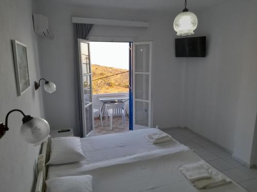 a white room with a bed and a table and a window at Silver view in Batsi