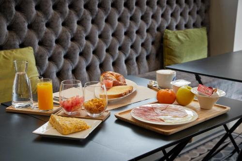 a table with two trays of breakfast foods and drinks at Hotel Iriguibel Huarte Pamplona in Huarte