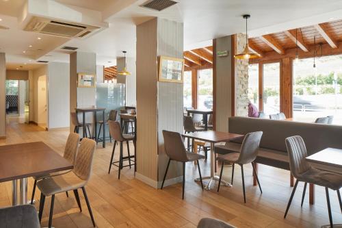 a restaurant with tables and chairs and a bar at Hotel Iriguibel Huarte Pamplona in Huarte