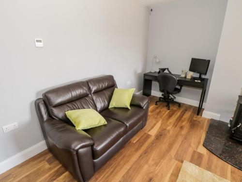 a living room with a leather couch with two yellow pillows at Tí Tom Nárta in Trawbaun