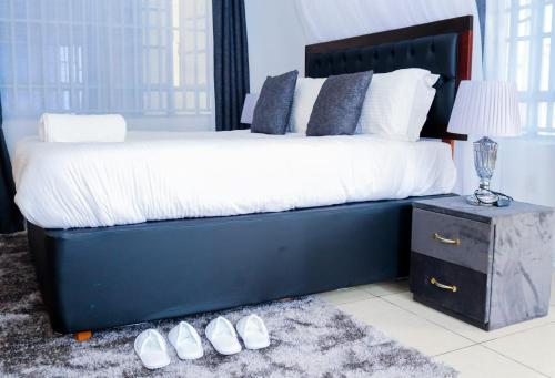 ein Schlafzimmer mit einem großen Bett und einem Paar Schuhe in der Unterkunft Sofitel 4 bedrooms maisonette Milimani in Kisumu