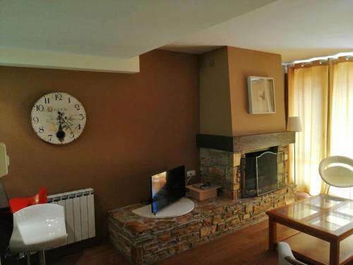 a living room with a fireplace and a clock on the wall at Los Altos de Escarrilla - tucasaenlospirineos in Escarrilla