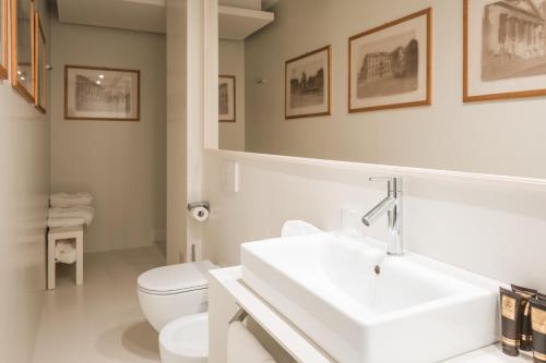 a white bathroom with a sink and a toilet at Royal Palace Hotel in Turin