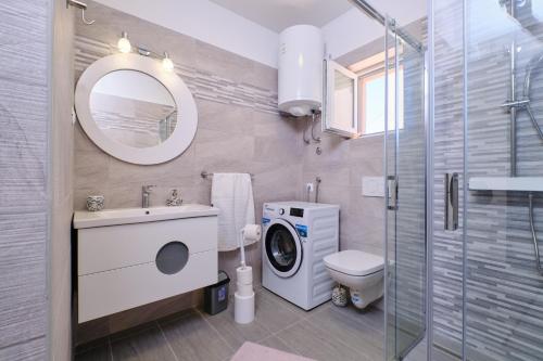 bagno con lavandino e servizi igienici e lavatrice. di Apartment Kaleta a Sveti Jakov