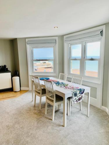 a dining room with a table and chairs and windows at The Beachfront Lookout a Stunning Apartment with Perfect Sea View in Worthing
