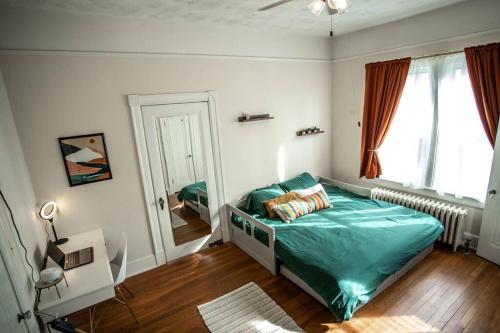 a bedroom with a bed with a green comforter and a window at Charming 1932 Craftsman - The Bohannon House in Luray