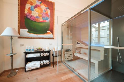 a bathroom with a glass shower and a painting of a flower vase at Royal Palace Hotel in Turin