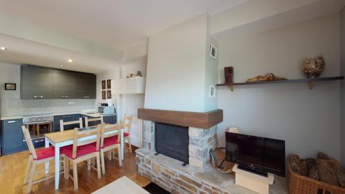 a living room with a fireplace and a table and a television at Los Altos de Escarrilla - tucasaenlospirineos in Escarrilla