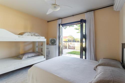 a bedroom with two beds and a sliding glass door at Casa Guaratuba-Barra do Saí - "Recanto de Milady" - 80 m da Praia in Guaratuba