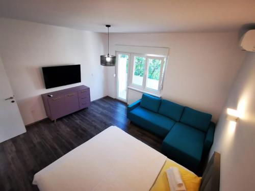 a living room with a blue couch and a tv at Apartman Smokva in Vodice