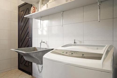 a bathroom with a sink and a washing machine at Casa Guaratuba-Barra do Saí - "Recanto de Milady" - 80 m da Praia in Guaratuba