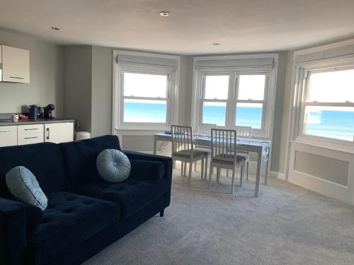 a living room with a couch and a table and chairs at The Beachfront Lookout a Stunning Apartment with Perfect Sea View in Worthing