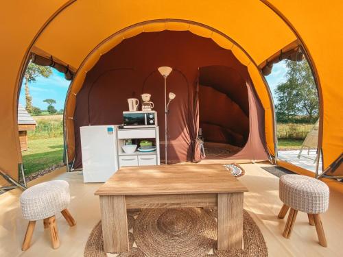 a tent with a table and two chairs and a refrigerator at Camping La Tourelle in Plémy