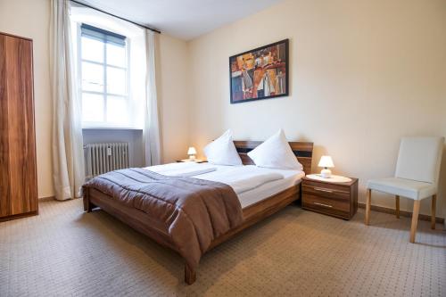 ein Schlafzimmer mit einem Bett, einem Stuhl und einem Fenster in der Unterkunft Gästehaus Moselkloster in Trittenheim