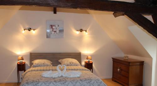 a bedroom with a bed with two white swans on it at Gîtes à l'ombre des chênes in Châteauvieux