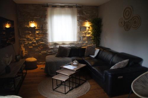 a living room with a black leather couch and a table at Mon petit cocon in Jalhay