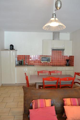 uma cozinha com uma mesa e algumas cadeiras vermelhas em Atlantic Hôtel em Saint-Pierre-dʼOléron